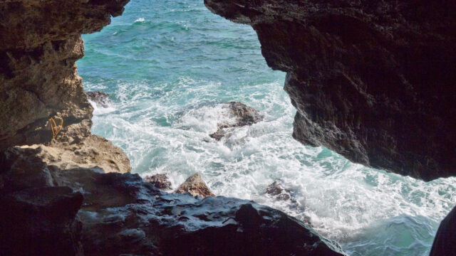 Image of the sea crashing against rocks, taken from inside a cave.