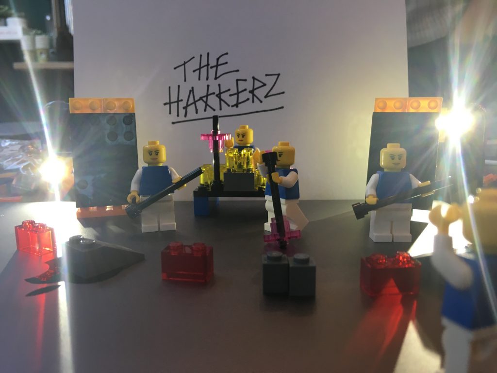 Four lego people in a band called The Hakkerz with musical equipment and lighting