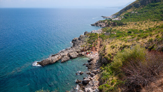A picture looking from the hill path down to a beach whilst walking along the Zingaro Nature Reserve trail in Sicily.