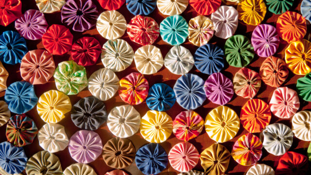 An image full of different coloured fabric roses. The roses are stitched together to form a table cover.