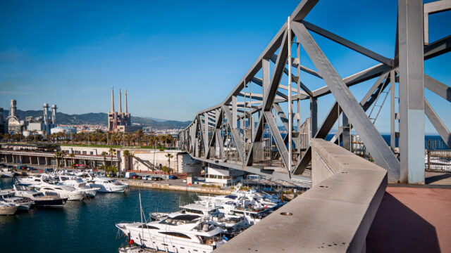 An image of a marina taken from the entrance to an angular bridge which is structured above the water