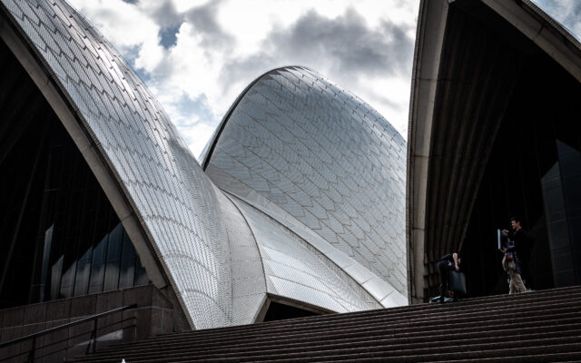 Photo of the Sydney Opera House taken from the steps. The photo is closely cropped so three curved elements of the roof take up almost all of the frame.