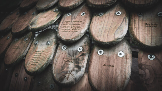 Close up of overlapping oval wooden panels. Each panel has a message written on it such as 'I know we can weather the storm'.